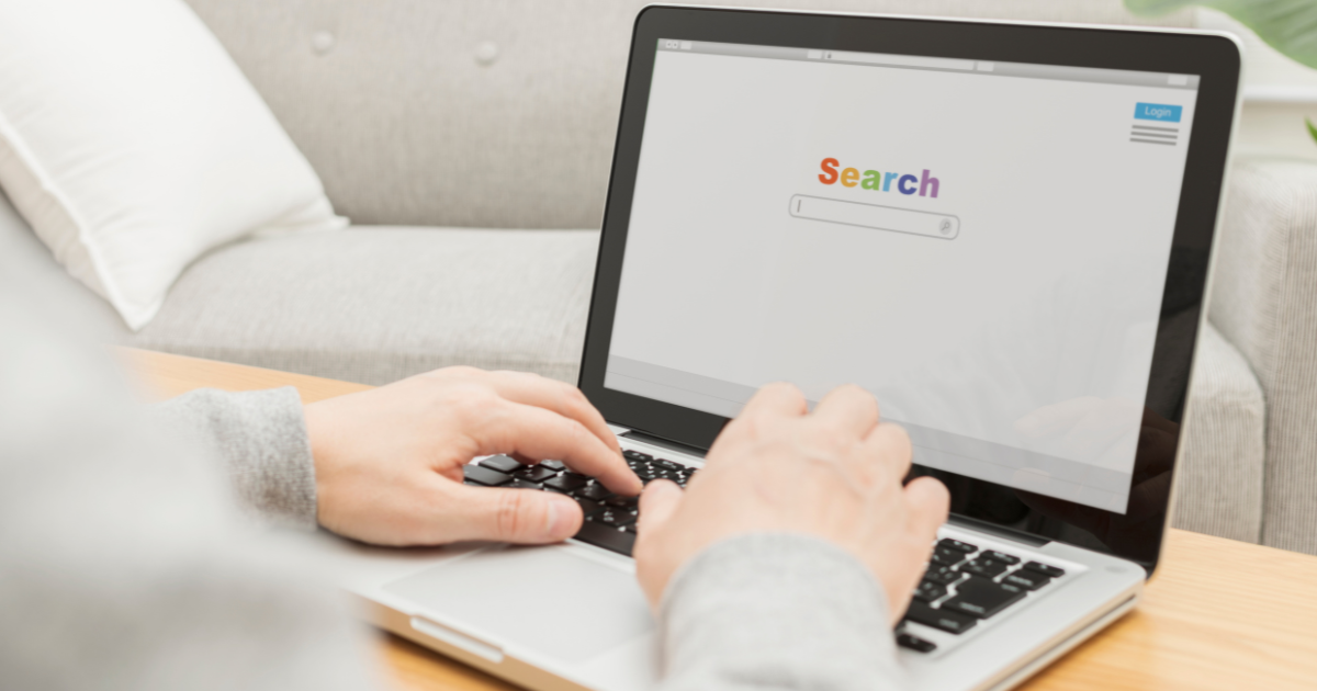 ノートパソコンで検索画面を開き、キーボードを操作している手元のアップ