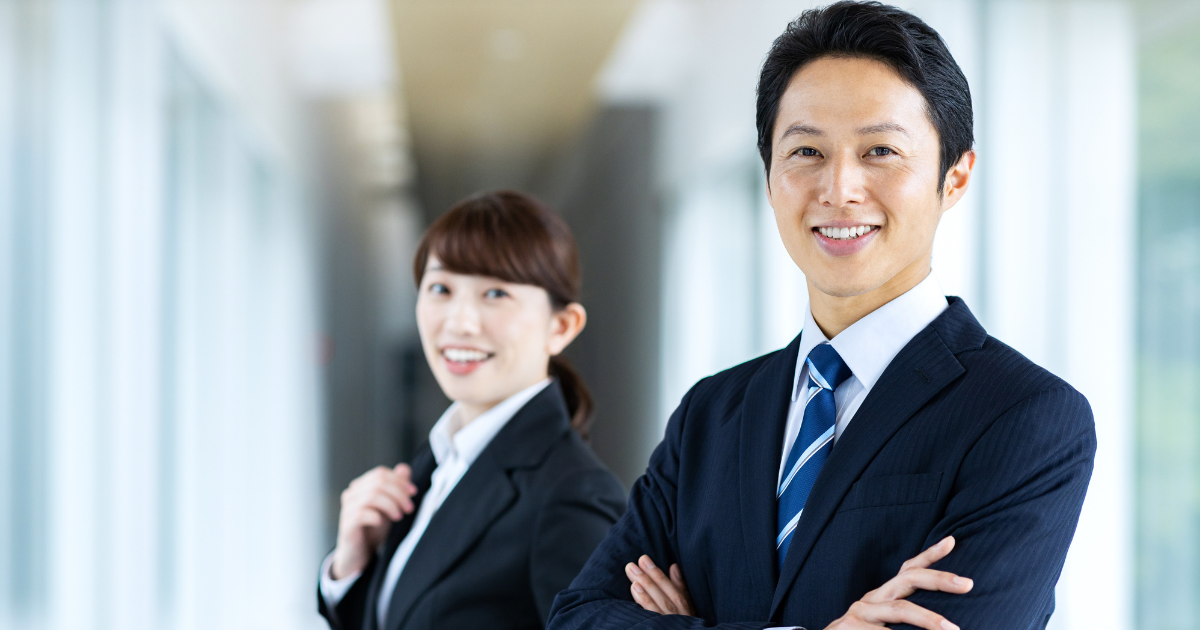 明るい通路で並んで立つ男女のビジネスパーソン