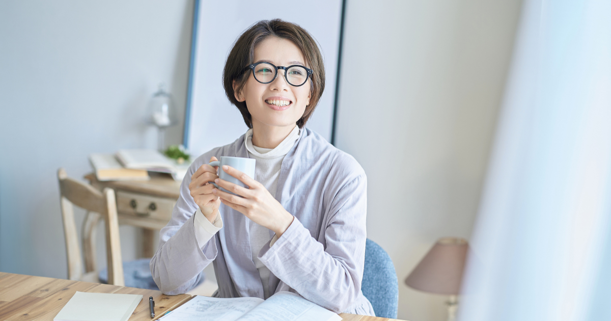 マグカップを両手で持ち、笑顔でくつろぐ女性