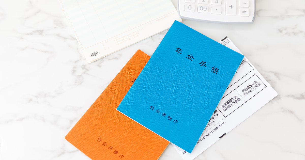 デスクに置かれたオレンジと青の年金手帳や書類