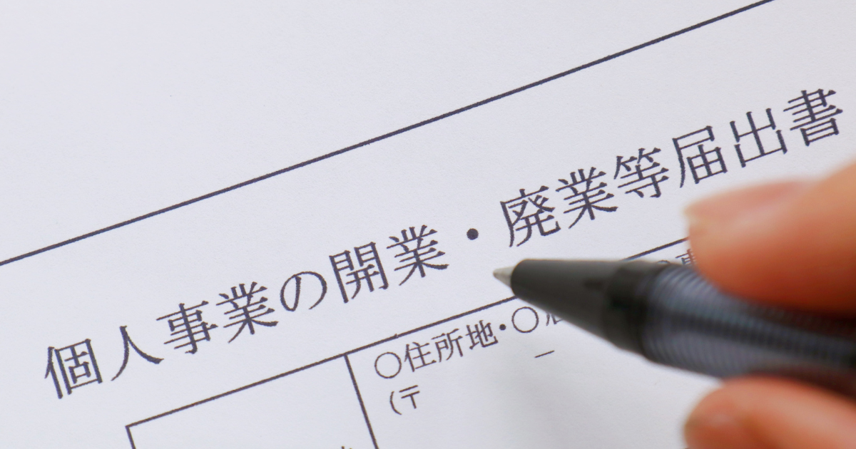 開業届の書類にペンで記入する手