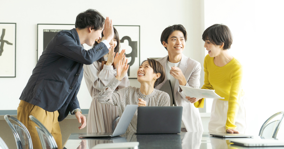オフィスで笑顔でハイタッチをするビジネスパーソンたち