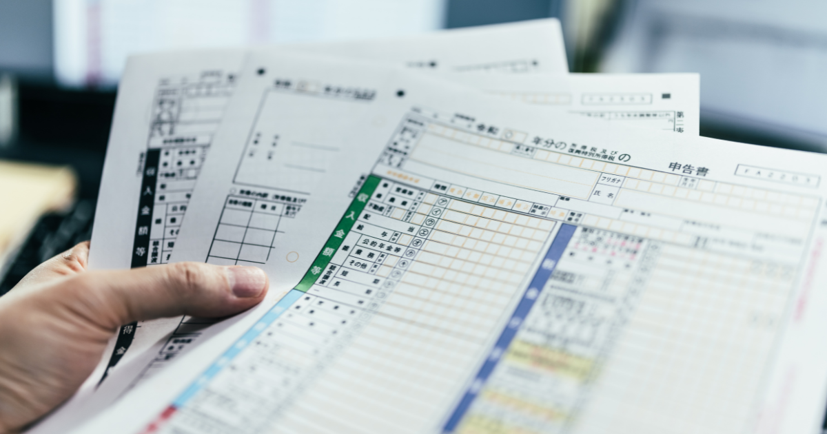 複数枚の確定申告書類を持っている手元