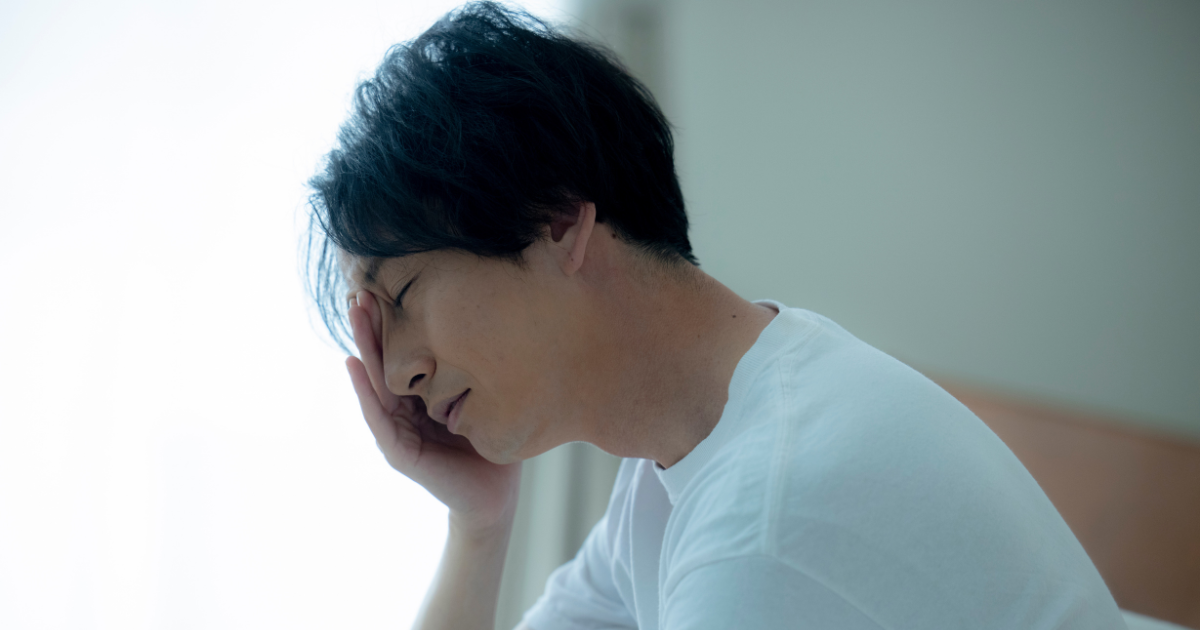 室内で頭を抱えて悩む男性の横顔