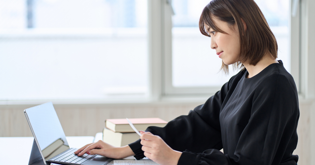レシートを持ってパソコンで作業する女性